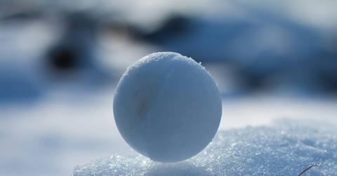 A round snowball is pictured atop a block of snow.