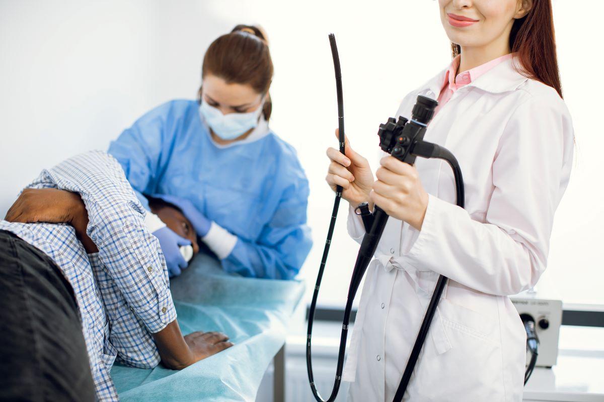 Female doctor holding an endoscope to perform a colonoscopy on a male patient