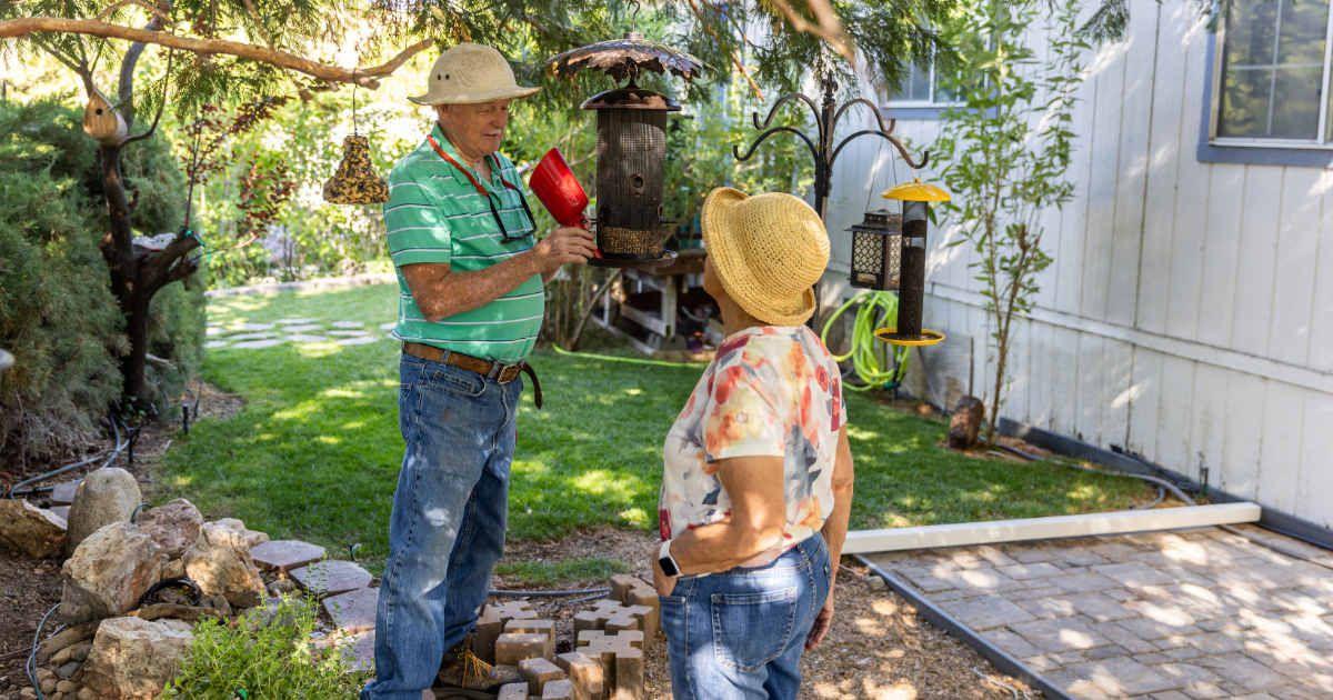 A retired couple is outside their home installing a bird feeder in the garden. (Representative Cover Image Source: Getty Images | Jason Doiy)