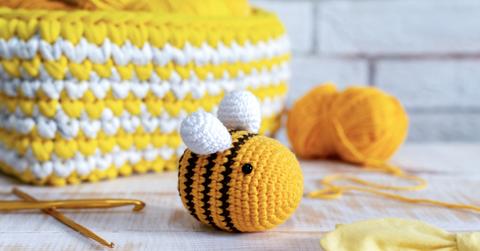 A bright yellow crochet bee on a white table.