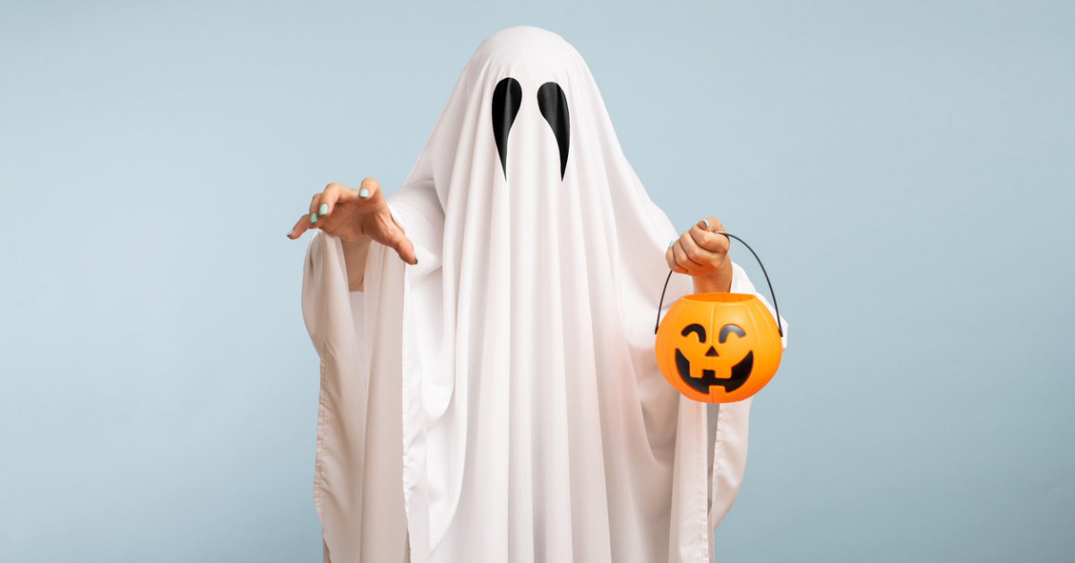 A woman wears a sheet with two black eye patches to dress up as a ghost