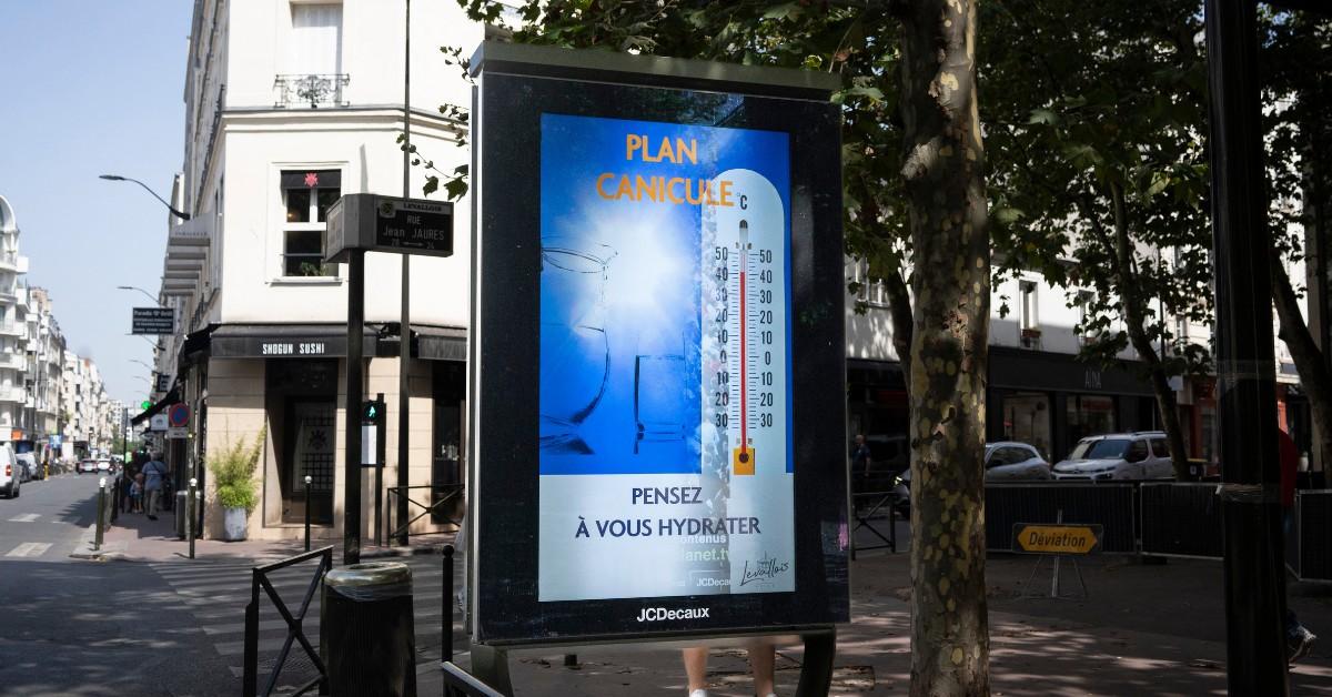 A bus stop sign in Paris announces the city's heatwave plan is in effect in French